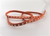 Imiteret læder bånd varm orange med nitter. Brug det til pynt omkring lys eller lav dit eget armbånd. Længde ca. 48 cm. Brede 0,5 cm.